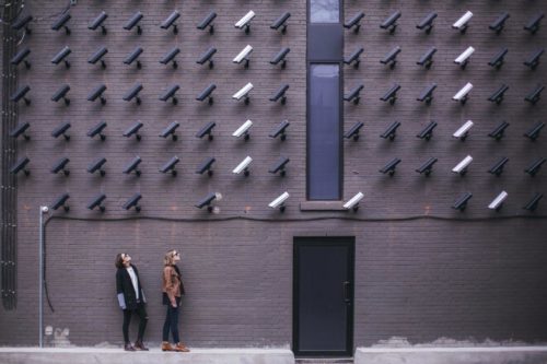 Two people looking up at a wall covered in CCTV cameras