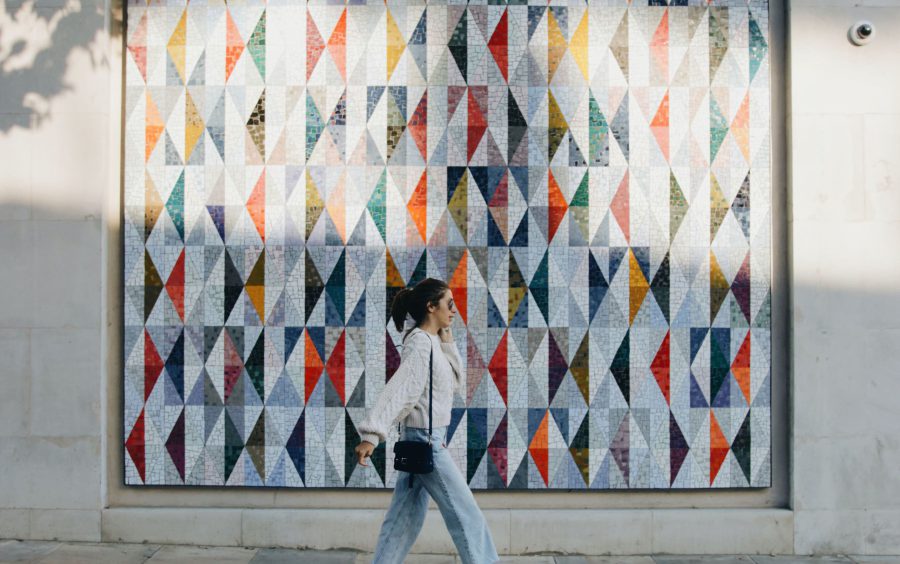 Woman walking past a large mural.